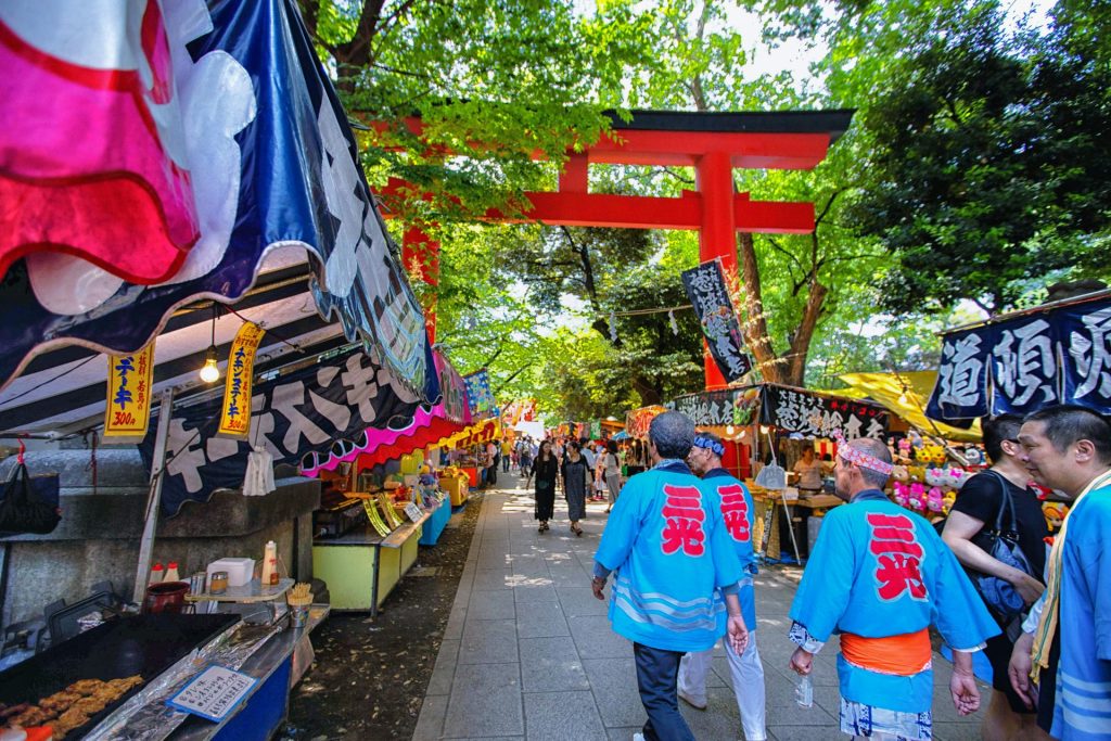 Lebhafte Szene bei einem traditionellen japanischen Straßenfest in Tokio mit farbenfrohen Ständen und Besuchern.